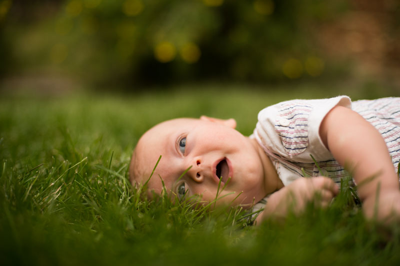 baby laughing and laying in grass